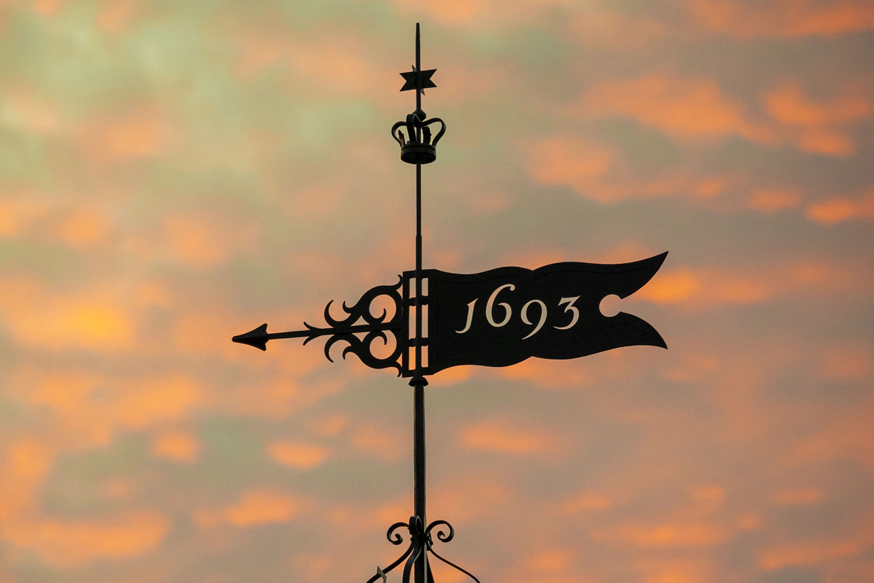The sky is illuminated from a sunset behind a weathervane.