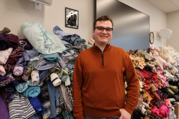 Dominic DiNunzio stands near a stack of rolls of fabric.