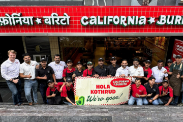 A large group poses for a photo in the entrance to a California Burrito.