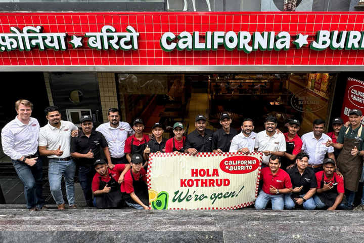 A large group poses for a photo in the entrance to a California Burrito.