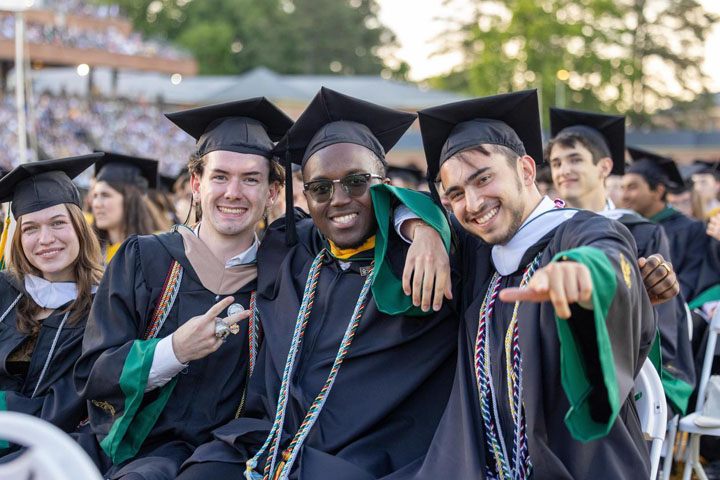 People in caps and gowns smile for a photo together.