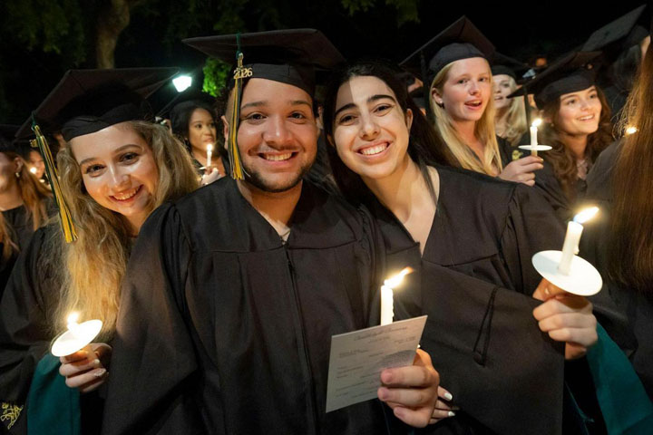 People in caps and gowns hold candles.