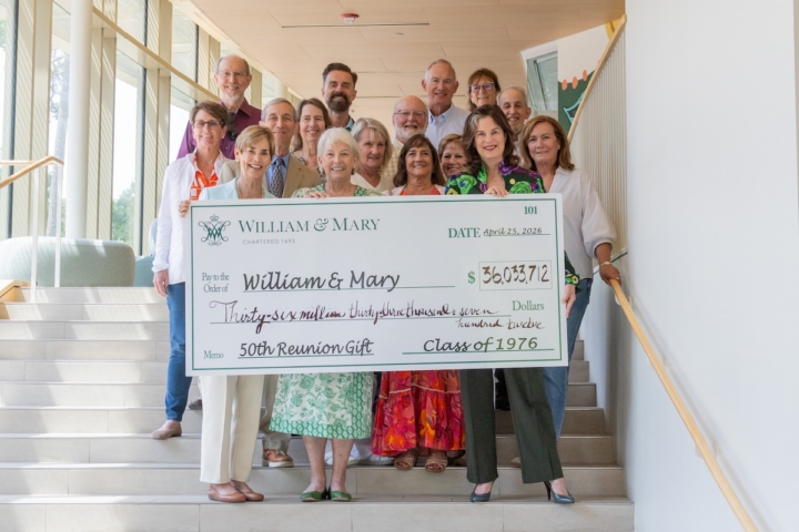 People stand on stairs and hold a large check.
