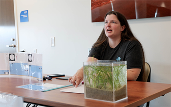 A person sits at a table with a small aquarium on it.