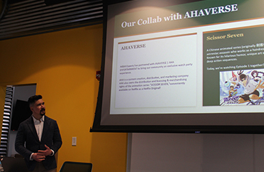 A person in a suit stands next to a screen that says "Our collab with AHAVERSE"