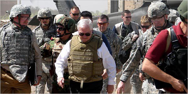 People in military uniforms and helmets walk near a helicopter.