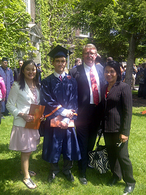 Three people take a photo with a person in a cap and gown.