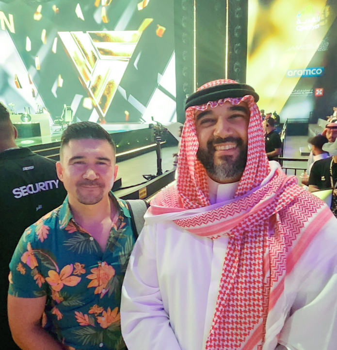 Two people take a photo together in front of a stage.
