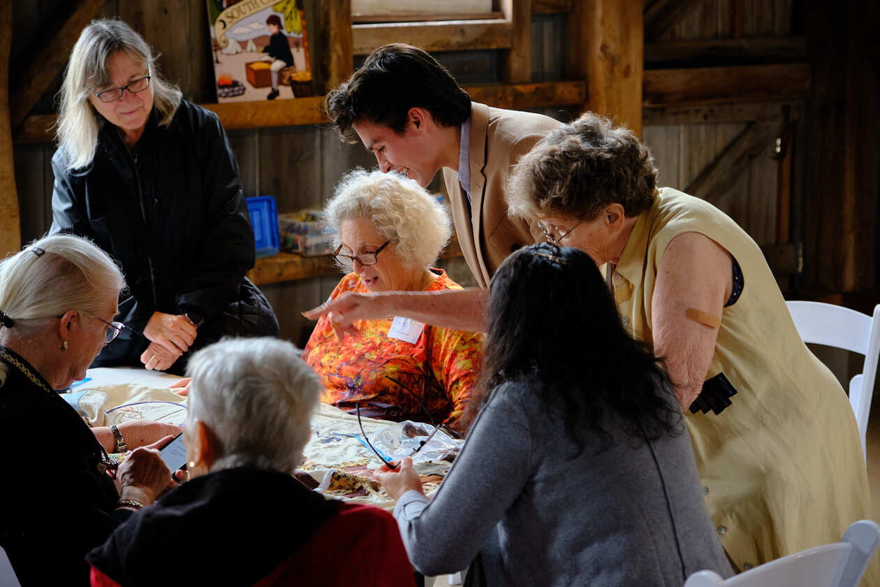 Stefan Romero, creator of the America's Tapestry project, consults with volunteer embroiderers completing one of the 13 panels