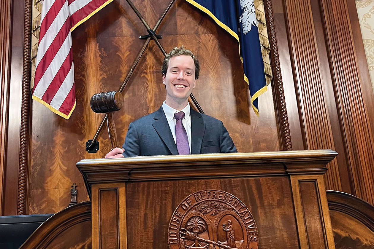 A person holds a gavel while standing at a wooden podium.