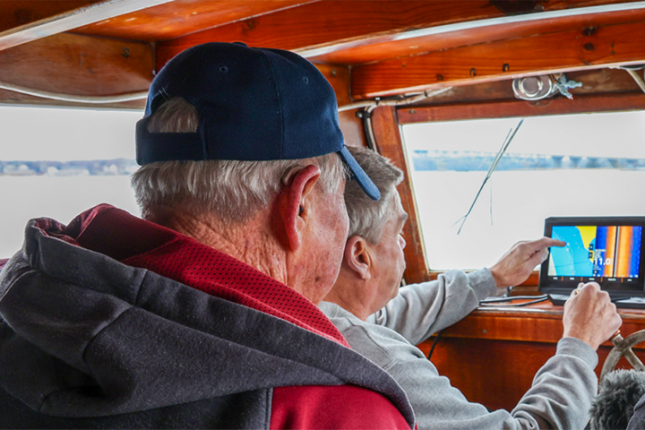 Two people look out from the bridge of a boat.