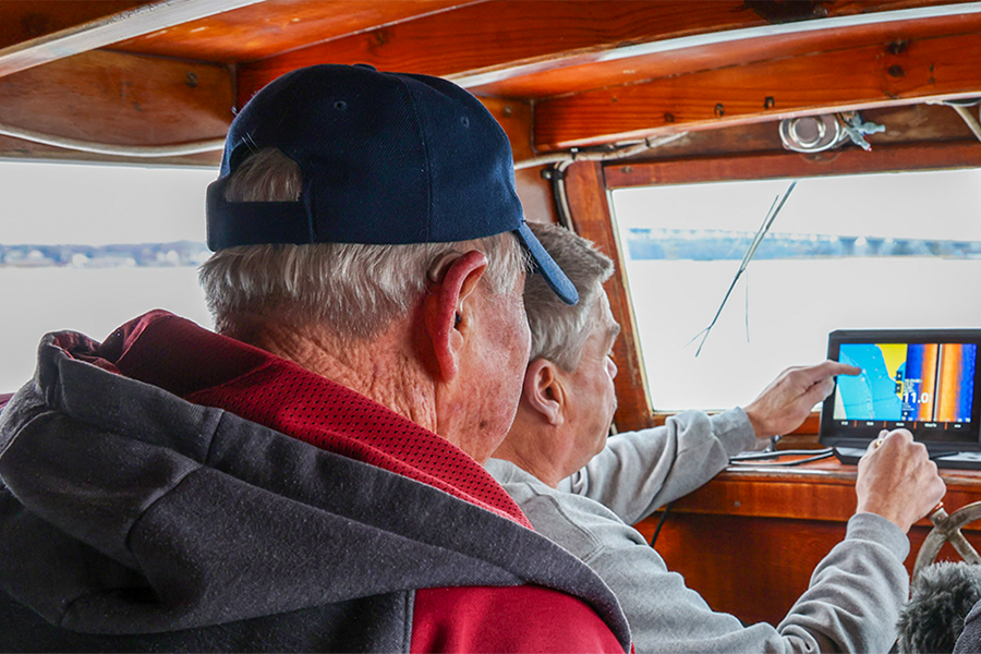 Two people look out from the bridge of a boat.