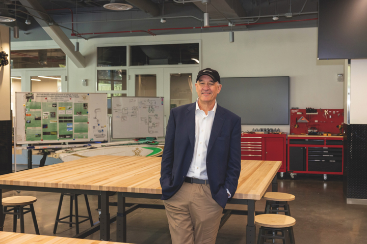Bob Wise stands in front of a table in a large room.