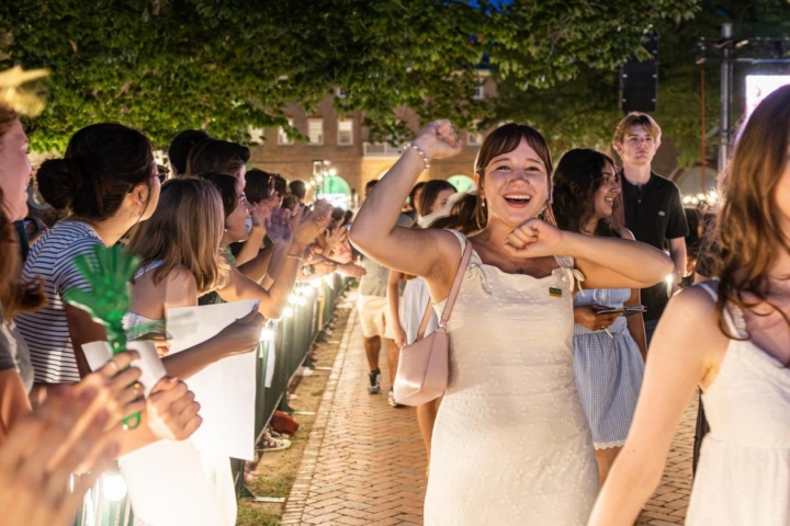 A person pumps their fists in the air after walking through the Wren Building.