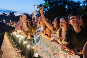 Returning students wave signs and trade high fives as new students walk through the Wren building for opening convocation.