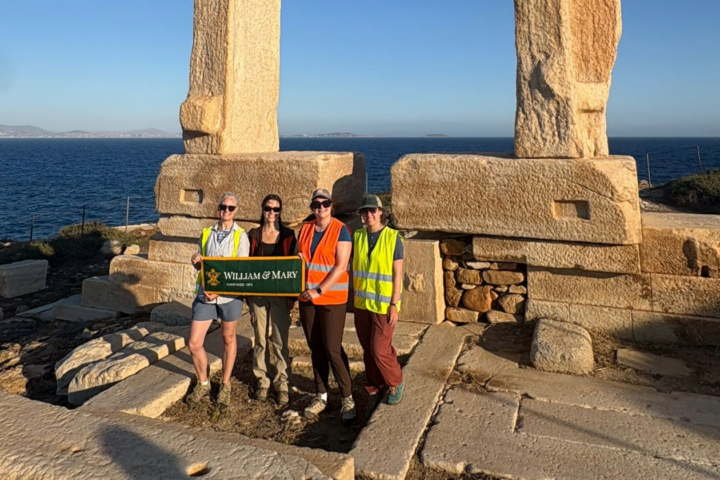This is a photo of a W&M research team — Jess Paga, Maya Parfitt, Phoebe Kirsh, and Paige Martin — standing in front of the unfinished temple on Palatia, an islet off the coast of the Greek island Naxos.