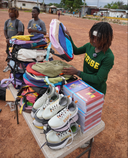 This is a photo of W&M soccer playerZeta Kromah before a table laden with donated school supplies and sports gear. 