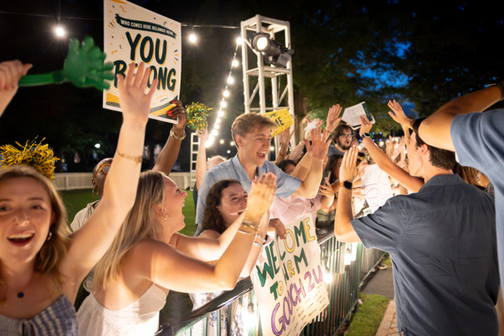 People cheer and hold signs while high-fiving others.