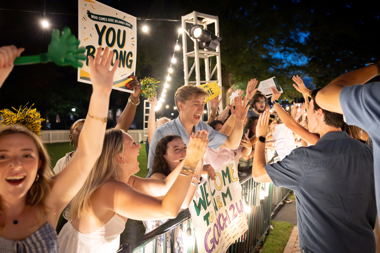 People cheer and hold signs while high-fiving others.