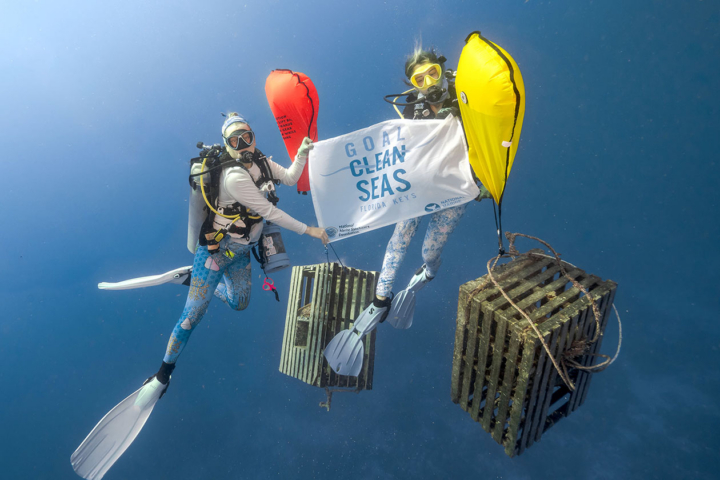 Two divers hold up a sign under water.