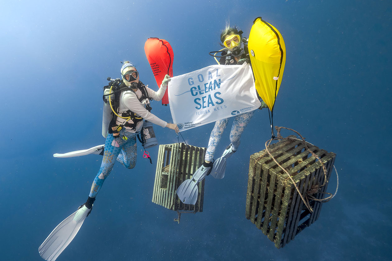 Two divers hold up a sign under water.