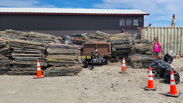 A person stands next to piles of compressed lobster traps.