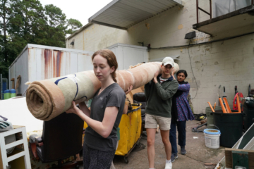 this is a photo of W&M students carrying a huge rolled carpet out of Habitat for Humanity's ReStore as part of a service project.