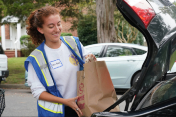 A student volunteers to help the House of Mercy bring food from its pantry to those in need.