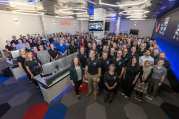 A group photo shows people standing in a NASA work room.