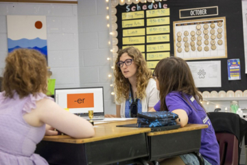 A teacher talks with students in a classroom.