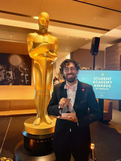 Arjun Fischer poses with the award he won for his documentary