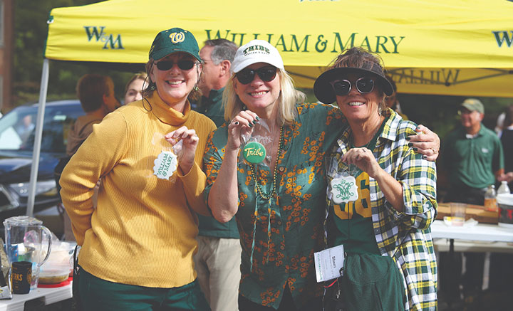 Three people take a photo together while holding up bags with W&M-themed cookies.