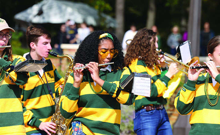 A person in a pep band plays a flute.
