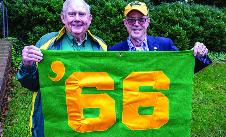 Two people hold a green sign that says '66.