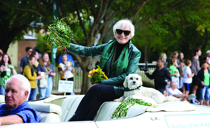 Glenn Close waves a pom-pom while riding on the back of a convertible.