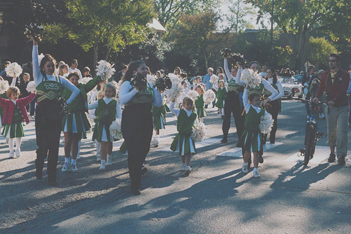 Children in cheerleading uniforms raise pom-poms.