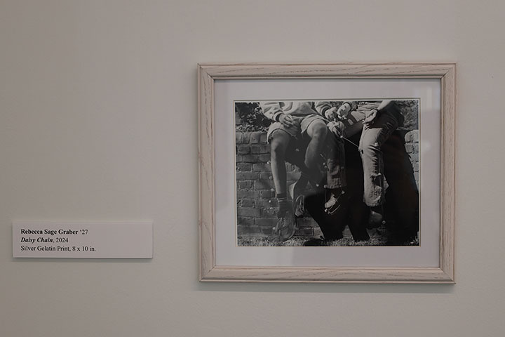 A framed, black and white photo of two people sitting on a wall.