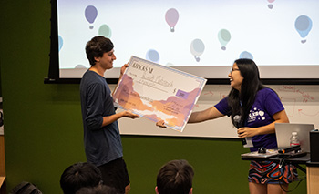 A person takes a large check from another person.