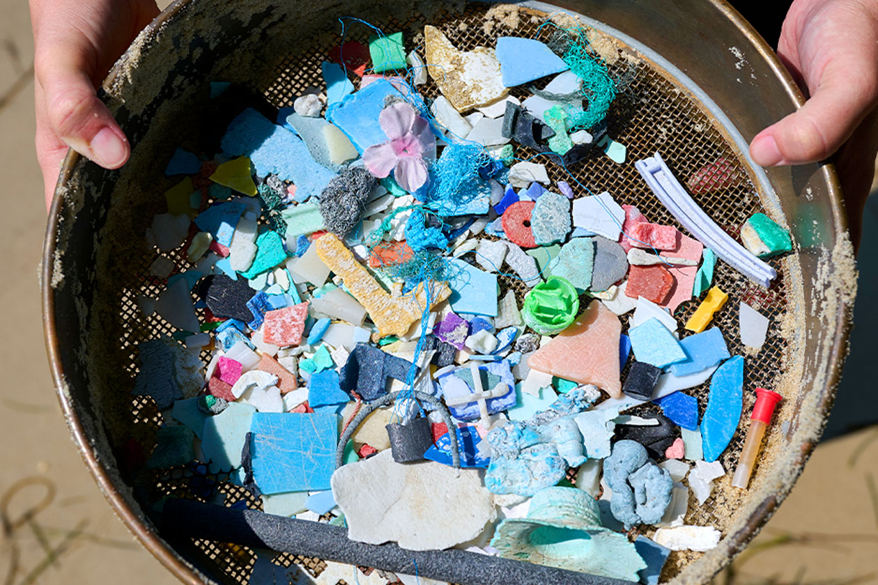 A person hold a sifter with plastic shards.