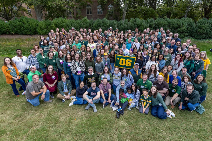 A ;large number of people pose for a photo together while holding an '06 sign.