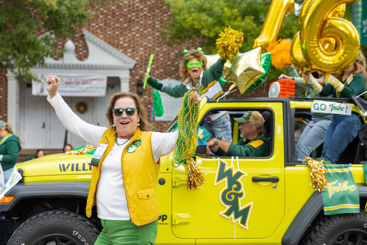 People hold pom-poms and cheer from a yellow Jeep.