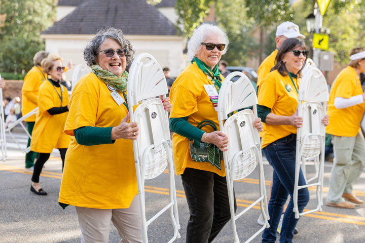 People in yellow shirts hold chairs.