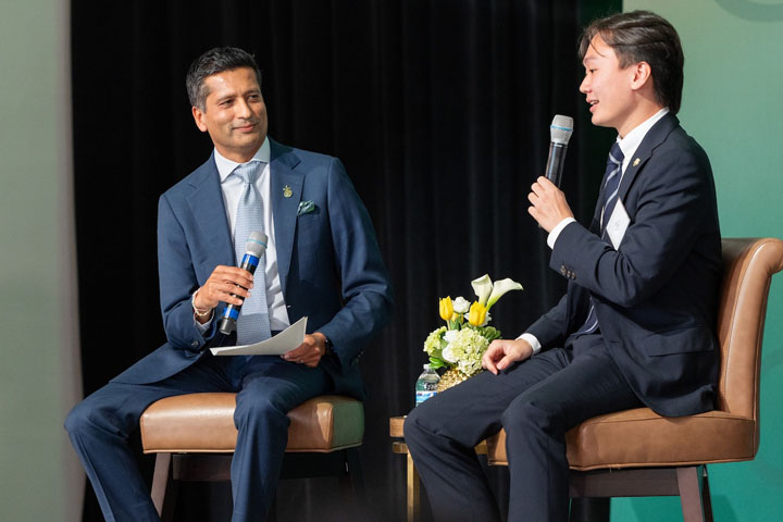 Two people on a stage hold microphones.