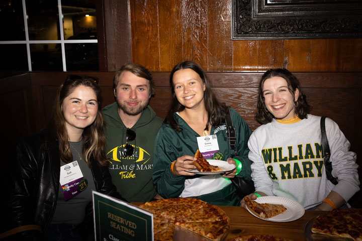 Four people pose for a photo together in a restaurant booth.
