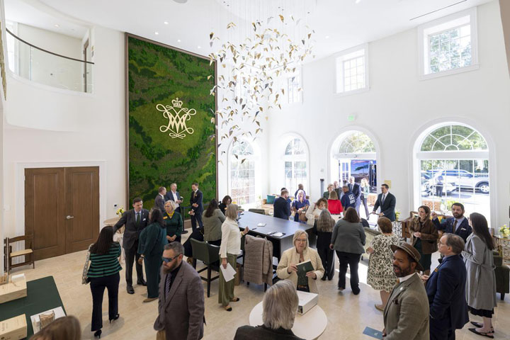 People gather in a lobby with a large, green wall.