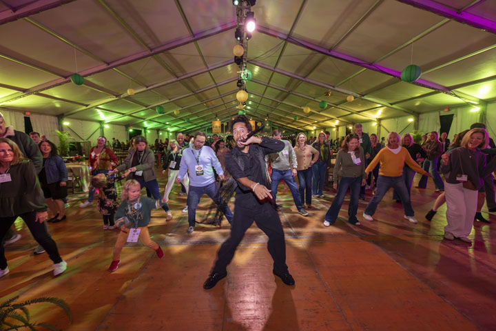 People dance on a floor while someone sings into a microphone.