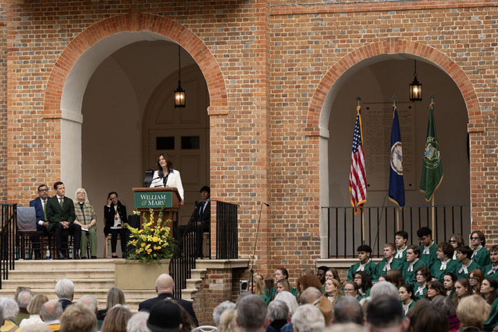 A person speaks at a podium in front of a large building.